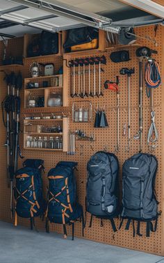 A garage with a pegboard backpacking gear wall displaying organized outdoor gear and backpacks. Outdoor Gear Storage Garage, Storage For Outdoor Gear, Garage Outdoor Gear Storage, Hiking Gear Peg Board, Outdoor Gear Room Ideas, Hiking Gear Storage Wall, Hiking Gear Wall, Camping Gear Storage Garage, Hiking Gear Storage Ideas