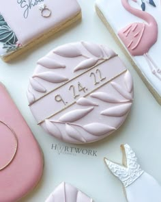 pink and white decorated cookies with wedding date on them, sitting next to each other