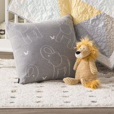 a stuffed animal sitting on top of a bed next to a pillow and quilted blanket