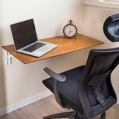 a laptop computer sitting on top of a wooden desk next to a black office chair