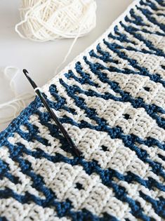 a crocheted blanket with yarn and knitting needles