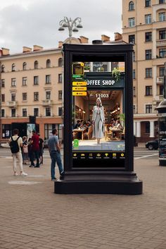 a large advertisement sign on the side of a city street with people walking around it