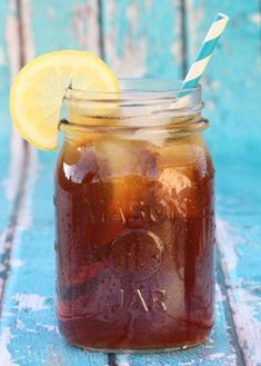 a mason jar filled with liquid and a lemon wedge on the side, sitting on a blue wooden table