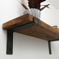 a wooden shelf with metal brackets holding a plant