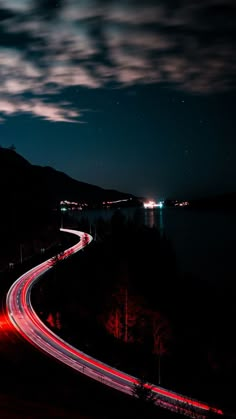 a long exposure shot of a highway at night with light streaks on the road and mountains in the background