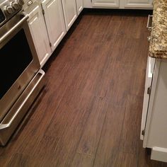 a kitchen with white cabinets and wood flooring on the counter top, along with an oven