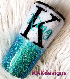 a blue and green glitter tumbler sitting on top of a white fur covered floor