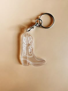 a pair of cowboy boots shaped keychains on a beige background with the word, boot