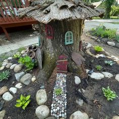 a tree stump with a small house built into it's base in the garden