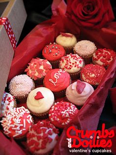 a box filled with lots of cupcakes covered in red and white frosting