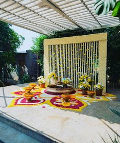 an outdoor area with flowers and decorations on the ground in front of a pergolated wall