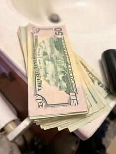 a stack of twenty dollar bills sitting on top of a sink