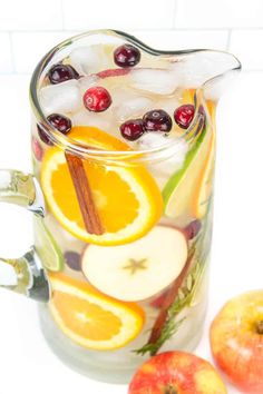 a pitcher filled with fruit and ice on top of a table