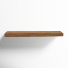 an empty wooden shelf against a white wall