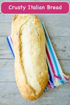 a loaf of bread sitting on top of a wooden table next to a striped towel