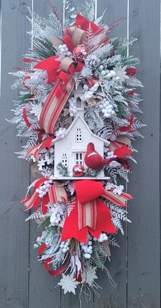 a wreath hanging on the side of a fence with red and white ribbons around it