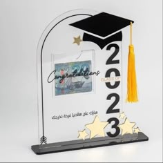 a clear glass award with gold stars and a graduation cap on the top, in front of a white background