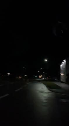 an empty street at night with the lights on and no one in the dark is seen