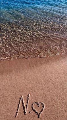 the word no 9 is written in the sand at the beach with blue water behind it