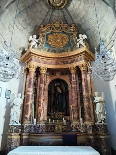 an ornate alter in a church with chandeliers hanging from it's ceiling