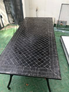 a black table sitting on top of a green tiled floor