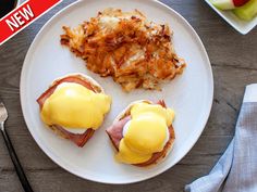 two eggs benedicts with bacon and cheese on a white plate next to silverware