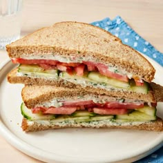 a white plate topped with a cut in half sandwich next to a glass of water