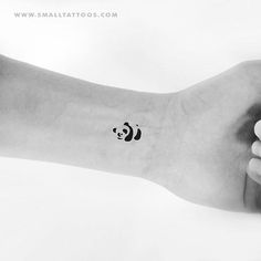 a person's arm with a small panda bear tattoo on the left side of their wrist