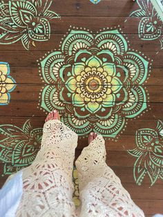 a person standing on top of a wooden floor next to a flower design wallpaper