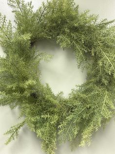 a close up of a wreath made out of branches on a white wall with no one around it