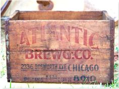 an old wooden crate sitting in the grass with some writing on it's side