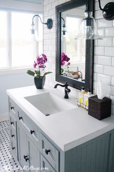 a bathroom with a sink, mirror and flowers in the vase on the counter top