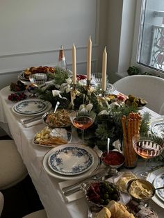 a table set with plates and candles for a holiday dinner or brunch party