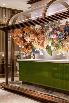 a display case filled with lots of flowers in front of a wall mounted glass window