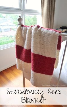 a crocheted blanket sitting on top of a wooden chair next to a window