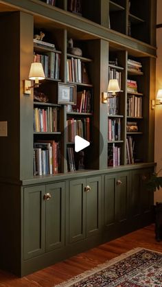 a living room filled with lots of green bookshelves next to a wall mounted lamp