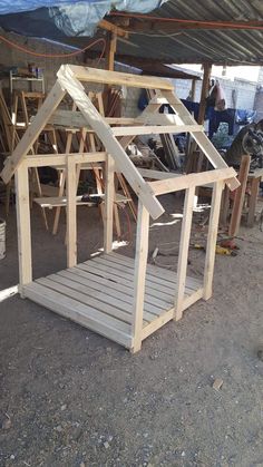 a house made out of wood sitting on top of a dirt ground next to a building