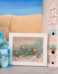 there is a picture frame with sea shells on it next to a lighthouse and other items