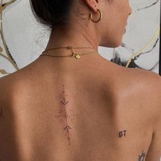 the back of a woman's neck with tattoos on her upper and lower back