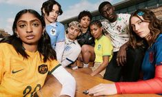 a group of people sitting at a table with soccer jerseys on and in front of them