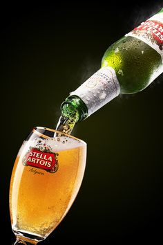 a beer being poured into a wine glass with the bottle in it's mouth