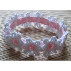 a crocheted bracelet with pink and white flowers on the end, sitting on a table