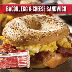 a bagel sandwich with bacon, egg and cheese on it next to a bagel wrapper