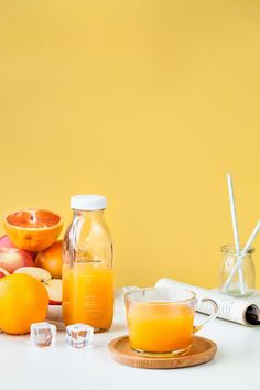 an orange juice is sitting on a table next to other fruits and glasses with strawberries