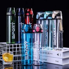 many different types of water bottles are stacked on top of each other in front of a stack of books