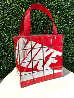 a red and white bag sitting on top of a table next to a green bush