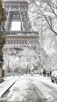 the eiffel tower is covered in snow as people walk by on a snowy day