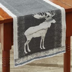 a table runner with an image of a moose on it, hanging from a wooden table