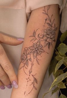 a woman's arm with flowers on it and dots in the middle, while she is holding her hand