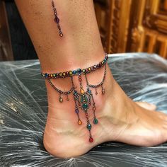 a woman's foot with a multi - colored beaded ankle chain on it